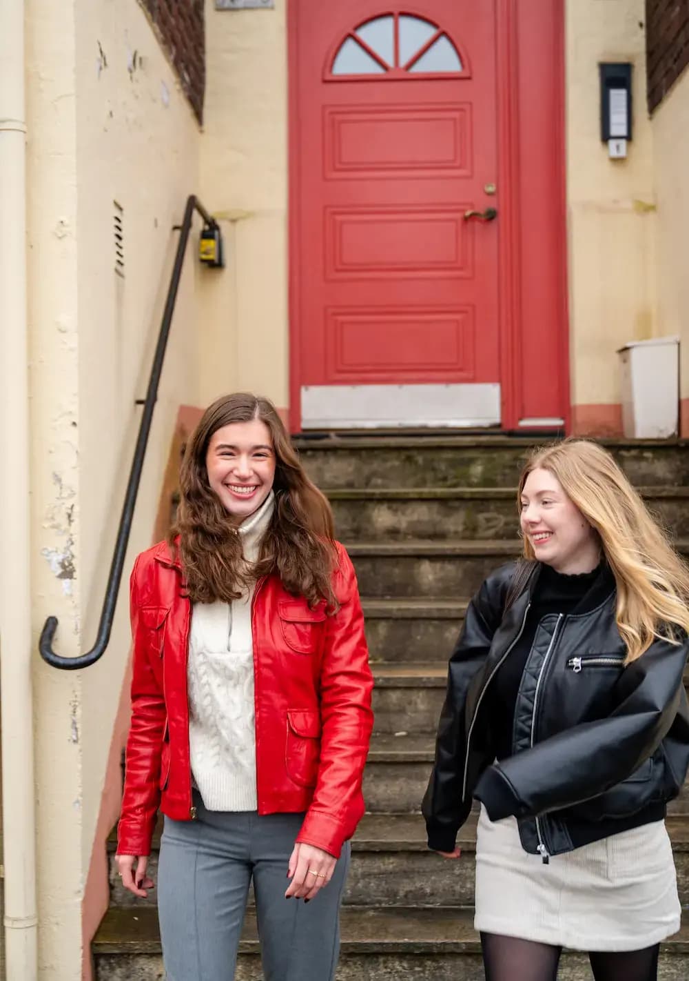 To venninner smiler på vei ut av en bygård